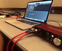 a red audio interface is connected to a laptop